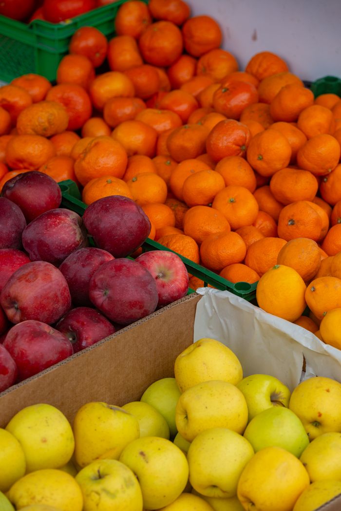 Vibrant display of assorted apples and citrus fruits at an outdoor market stall.